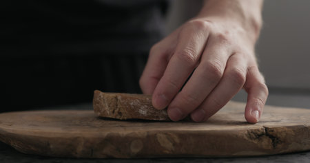 man put rustic ciabatta slice on wood boardの写真素材