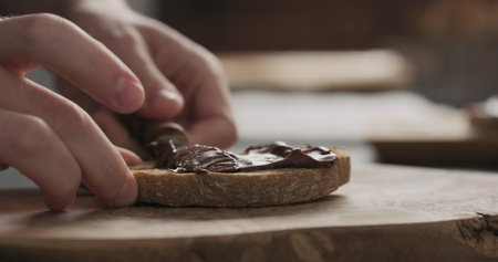 man spreading chocolate hazelnut spread on ciabatta slice on wood boardの写真素材