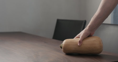 man put butternut pumpkin on walnut table