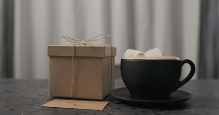 gift box near black cup with hot chocolate on concrete countertopの写真素材