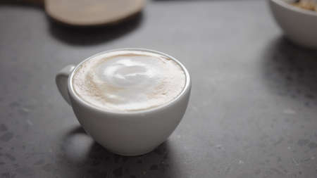 Pour steamed milk into espresso to make cappuccino on concrete countertop closeupの写真素材