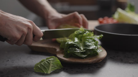 man hand cutting romaine lettuce on wood board to make saladの写真素材