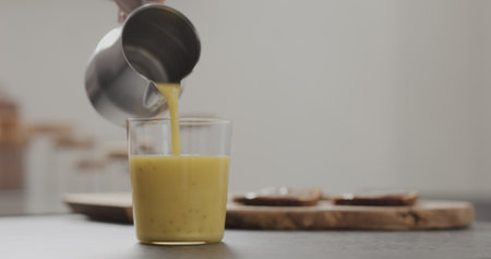 pour mango lulo smoothie into tumbler glass on concrete countertop with copy spaceの写真素材