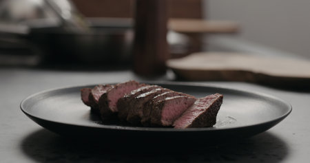 sliced beef steak on black plate on concrete countertopの写真素材