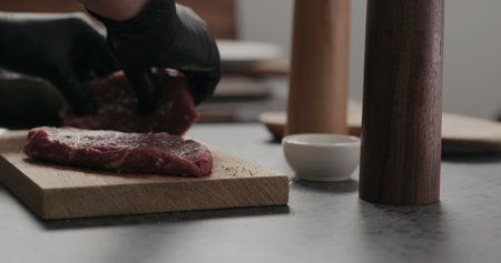 man rub seasoning into raw beef steak on oak boardの写真素材