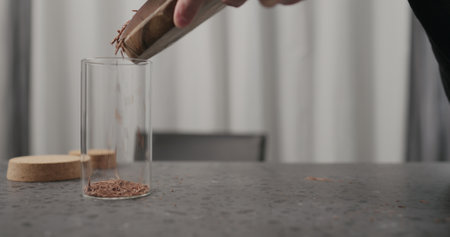 closeup man hands making dark chocolate flakes with knife on wood boardの写真素材