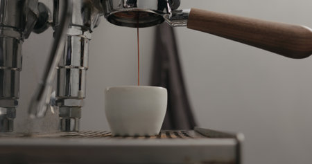 low angle shot of espresso extraction from naked portafilter into white cup