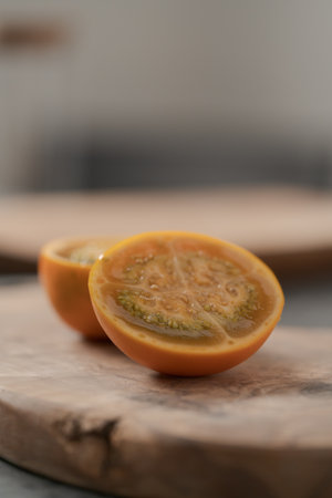 Lulo fruit sliced in halves on olive wood board on kitchen countertop