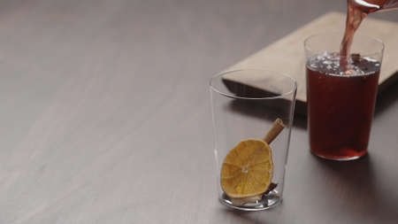 man hand serving mulled wine in thin tumbler glasses on walnut table