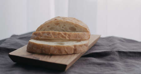 sliced ciabatta on olive board with window on backgorund