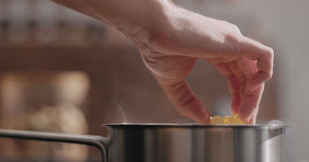 man hand put fettuccine pasta in saucepan with boiling water closeupの写真素材