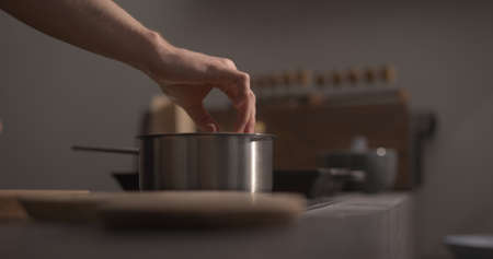 man hand put fettuccine pasta in saucepan with boiling water closeupの写真素材