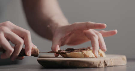 Man spreading chocolate hazelnut spread on baguette slices