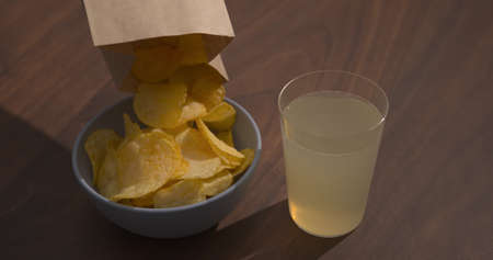 Man hand pour potato chips to blue bowl with ginger beer on background