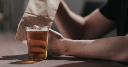 Man drinking amber color fizzy drink with bag of potato chipsの写真素材