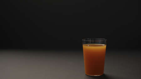 mango juice in tumbler glass on black paper background with copy spaceの写真素材
