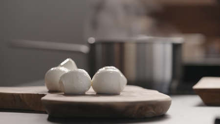 whole medium sized mozzarella balls on olive wood board