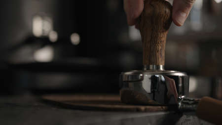 closeup of barista tamping fresh coffee in bottomless portafilter