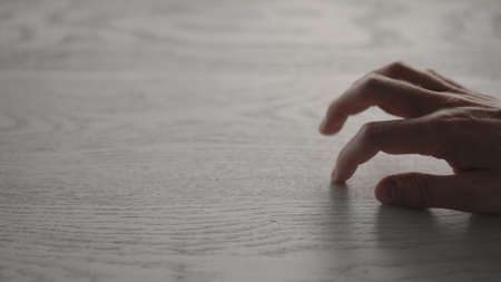 Closeup man hand finger tapping oak wood surfaceの写真素材