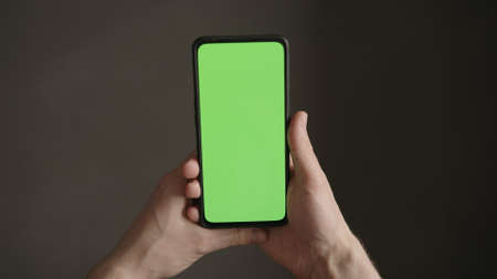 POV top view shot of man hold phone with green screen indoorの写真素材