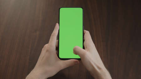 Man using phone with green screen on black wwalnut tableの写真素材