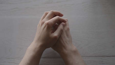 man hands on white oak table with window light while waitingの写真素材