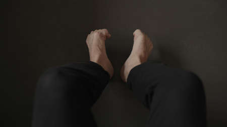 Man sitting on a couch and making feet streych excerciseの写真素材