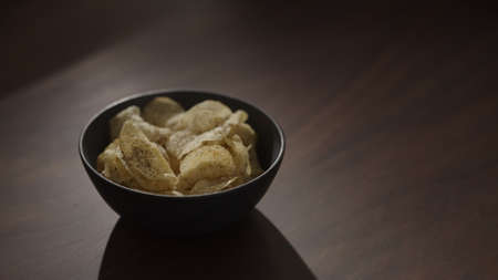 organic potato chips with black pepper in black bowl on walnut table