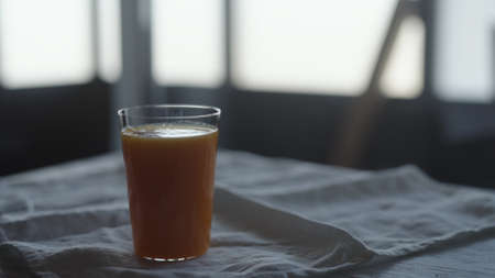 orange juice into tumbler glass on linen clothの写真素材