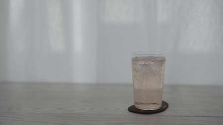 pour rose drink into tumbler glass on white tableの写真素材