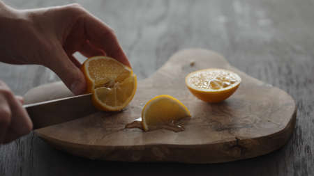 Man cutting sweet lemon on olive wood boardの写真素材