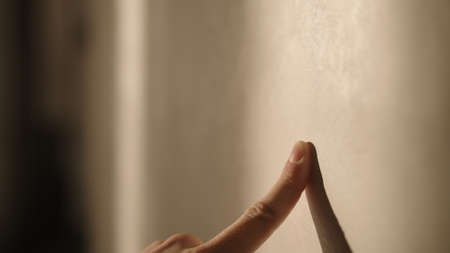 Man playing with sunlight indoor next to wallの写真素材