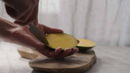 Man cut fresh ripe mango on olive board