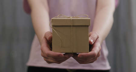 young woman stand and show brown gift box with twine bowの写真素材