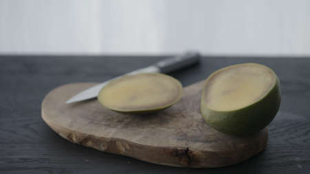 Sliced bad mango in halves on olive wood boardの写真素材