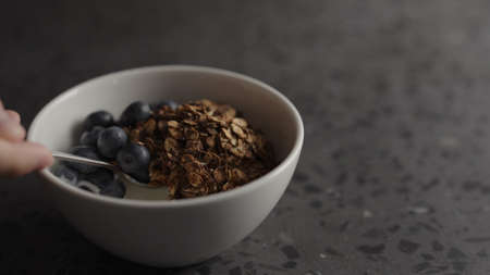 Man eat granola with yogurt and blueberries in white bowlの写真素材