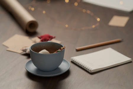 Cup of hot chocolate next to notepad and christmas decorationsの写真素材