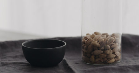 salted pistachios with black bowl on linen clothの写真素材