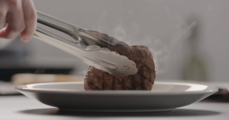 man put hot steak on white plateの写真素材