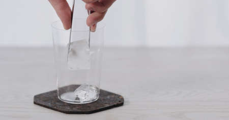 man put big ice rock into tumbler glass