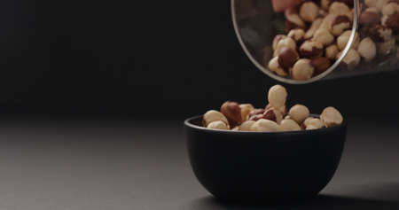 roasted hazelnuts falling into black bowl on black backgroundの写真素材