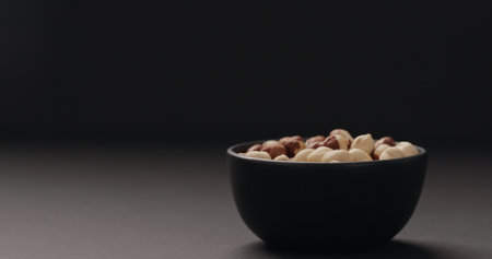 roasted hazelnuts in black bowl on black backgroundの写真素材