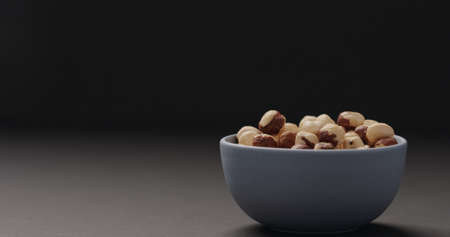 roasted hazelnuts in blue bowl on black background