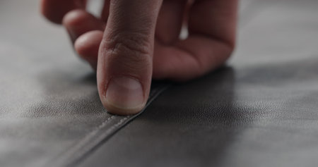 closeup man hand checking seam on soft gray leather clothesの写真素材