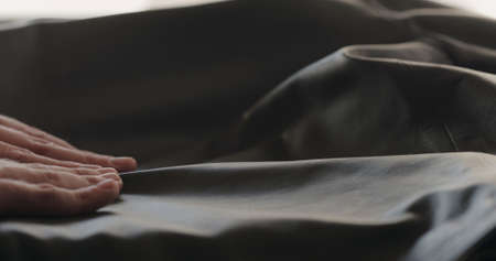 man hand checking soft gray leather clothes