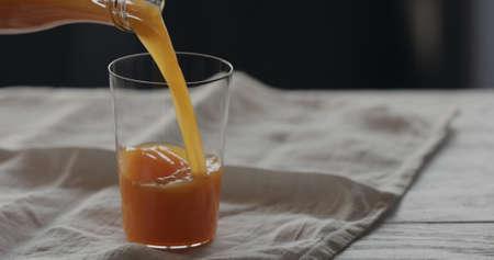 pour pumpkin juice in tumbler glass on linen clothの写真素材