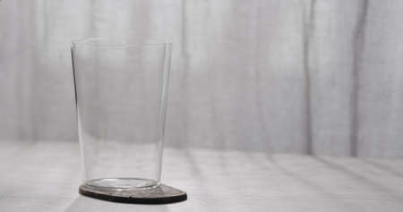 Empty tumbler glass on a white oak table with copy spaceの写真素材