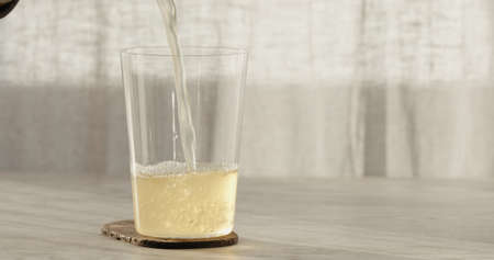 closeup pour ginger beer in a tumbler glass on oak table with copy spaceの写真素材