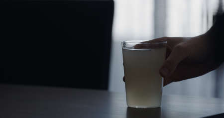 closeup man hand take lemonade in a tumbler glass from walnut table with copy spaceの写真素材