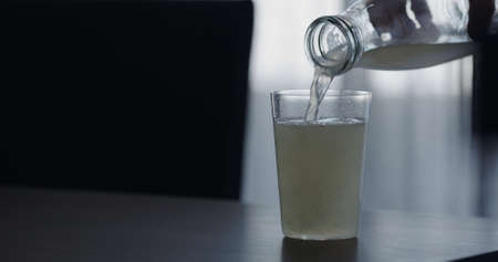 closeup pour lemonade in a tumbler glass on walnut table with copy spaceの写真素材